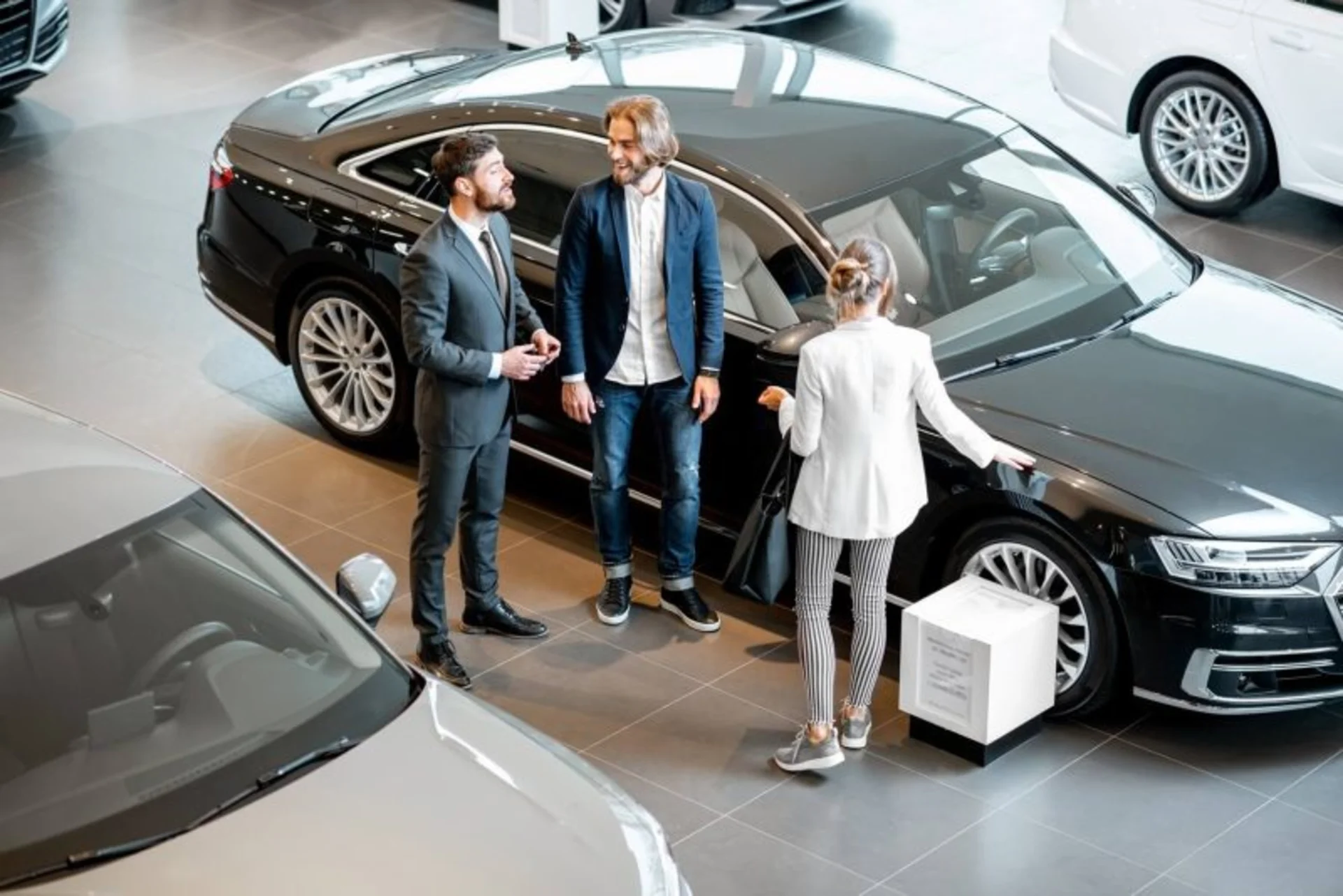 business-couple-with-salesperson-in-the-car-showroom